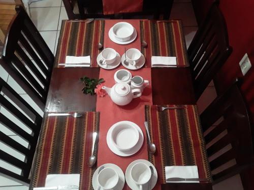 a table with white plates and cups on it at Vuya Nathi Bed and Breakfast in Manzini
