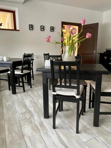 a dining room with black tables and chairs with pink flowers at Villa Kmeller in Lviv