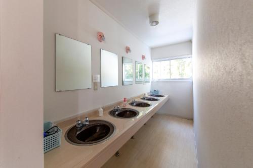 a bathroom with three sinks and two mirrors at Summer Leaves in Hakuba