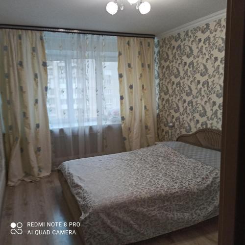 a bedroom with a bed and a window with curtains at Апартаменты на Московском проспекте in Kaliningrad