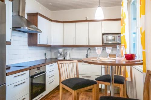a kitchen with white cabinets and a table with two chairs at Villa Haapaniemi in Iisalmi