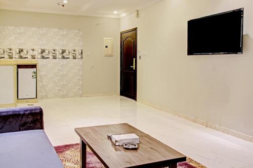 a living room with a table and a tv on a wall at Al Tamayoz Al Raqi - Bani Malik in Jeddah
