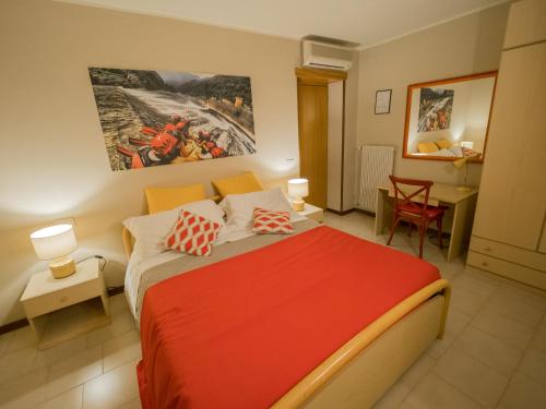 1 dormitorio con cama roja, escritorio y silla en Rafting Hotel Ai Cavallini, en Solagna