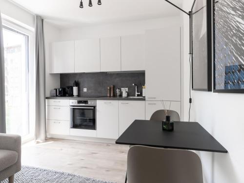 a kitchen with white cabinets and a black table at limehome Linz Hopfengasse in Linz