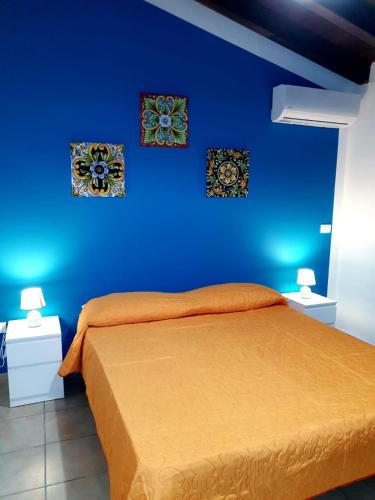 una camera blu con un letto e due quadri sul muro di Casa vacanza L'antico moderno a Terrasini
