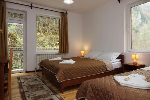 a hotel room with two beds and two windows at Семеен хотел Орфей in Teshel
