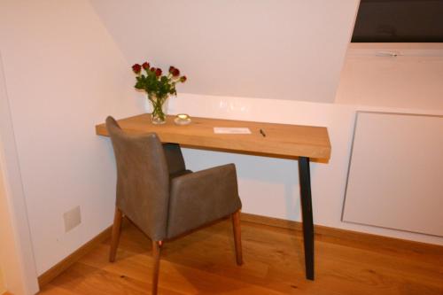 a wooden desk with a chair and a vase of flowers at wohnanders in Fürstenfeld