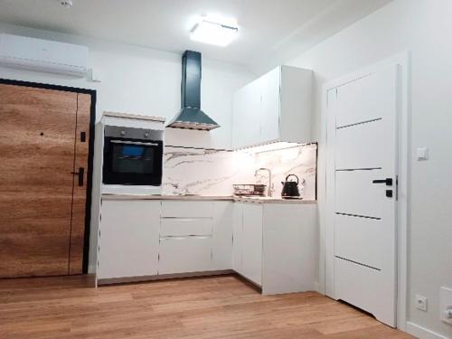 a kitchen with white cabinets and a microwave at Apartamenty Radom Klwatecka 20 in Radom