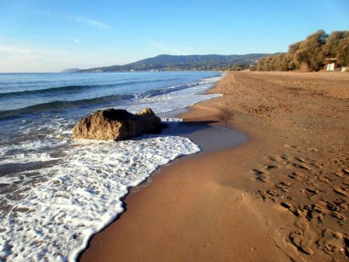 a beach with a rock and footprints in the sand at Koroni Zaga Beach- Seascape Luxury Villa Costiana in Koroni