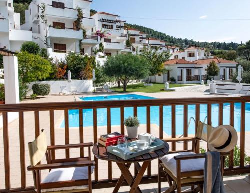a table and chairs on a balcony with a pool at Skopelos Summer Homes in Skopelos Town