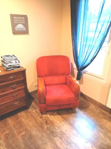 a red chair next to a dresser and a window at La résinière in Salles