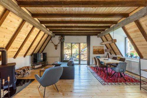 a living room with wooden ceilings and a table and chairs at Kežman Mountain Houses in Kopaonik