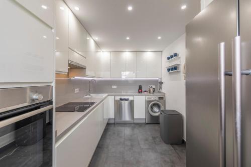 a kitchen with white cabinets and a washer and dryer at MEDANO4YOU Barefoot Beach House in El Médano