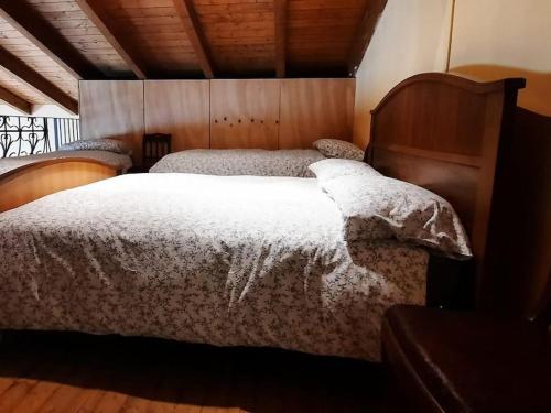 a bedroom with a large bed with a wooden headboard at Cascina Ca' Scarlatta - Your Mountain Holiday in Introbio