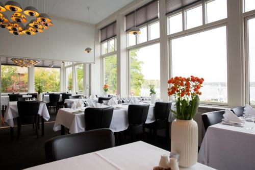 a dining room with tables and chairs and windows at Hotel Troense in Svendborg