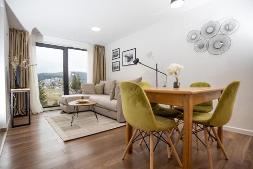 een woonkamer met een tafel en groene stoelen bij Vista Durmitor - luxury cabin in Žabljak