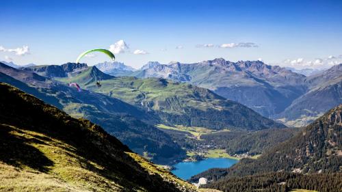 a paraglider is flying over a mountain valley at Central Sporthotel Davos in Davos