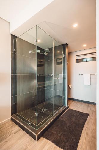 y baño con ducha de cristal y alfombra. en Umhlanga Arch Properties, en Durban