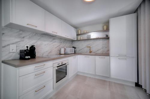une cuisine blanche avec des armoires et des appareils blancs dans l'établissement IMMOGROOM - Garden - Bikes - BBQ - Parking - AC, à Cannes