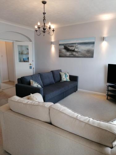 a living room with a couch and a chandelier at Sunrise View - Beachfront Apartment, Weymouth in Weymouth