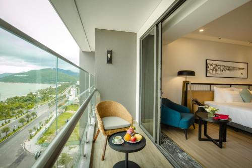 a hotel room with a balcony with a bed and a desk at FLC City Hotel Beach Quy Nhon in Quy Nhon