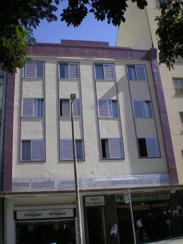 an apartment building with shuttered windows on a street at Hotel São Bento in Belo Horizonte