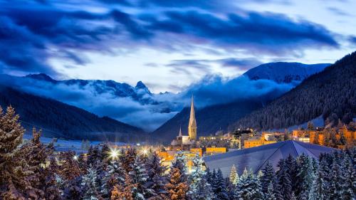 a town in the mountains at night with a church at Central Apartments Davos in Davos