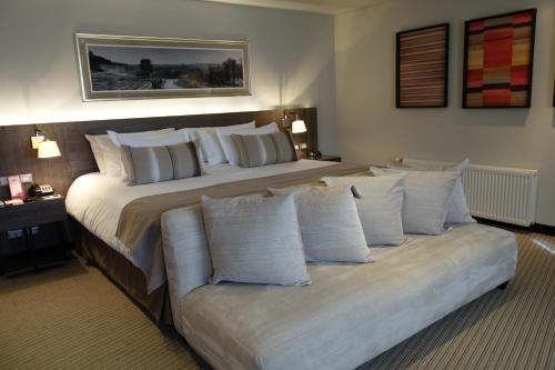 a bedroom with a large bed with white pillows at Hotel Los Españoles Plus in Santiago