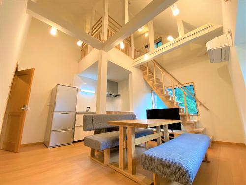 une salle à manger avec une table, des chaises et un escalier dans l'établissement 白馬パウダーマウンテン, à Hakuba