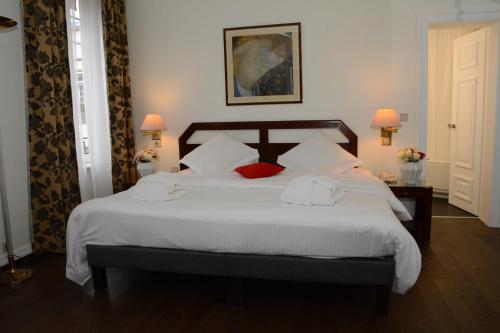 a bedroom with a large bed with white sheets and red pillows at Hotel Du Parc - Mulhouse Centre in Mulhouse