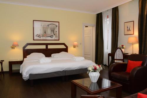 a hotel room with a bed and a chair at Hotel Du Parc - Mulhouse Centre in Mulhouse