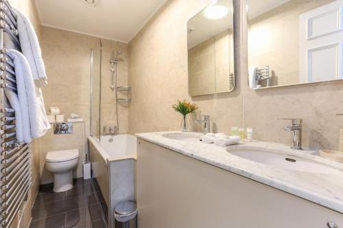 La salle de bains est pourvue d'un lavabo, de toilettes et d'un miroir. dans l'établissement Park Lane Apartments - Clarges Street, à Londres