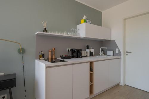 cocina con armarios blancos y encimera en limehome Flensburg Holm en Flensburg