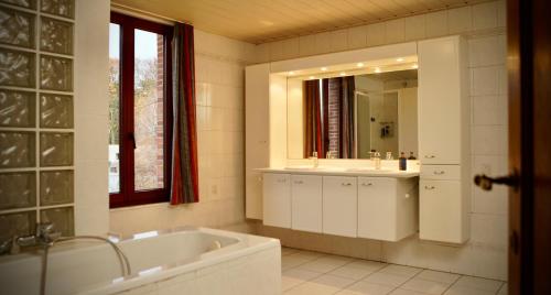 La salle de bains est pourvue d'une baignoire, d'un lavabo et d'un miroir. dans l'établissement De Strikker, à Balen