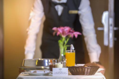 a man in a tuxedo standing behind a table with a tray of food at Gerasa Hotel in Amman