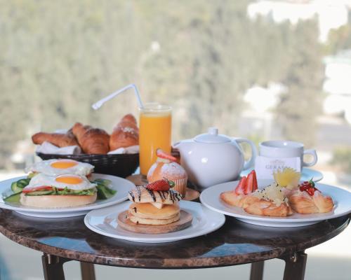 a table with plates of breakfast foods and a glass of orange juice at Gerasa Hotel in Amman