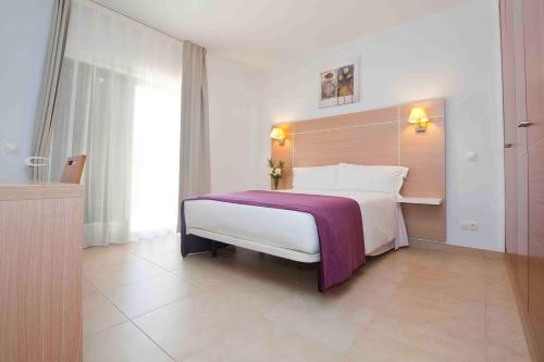 ein Schlafzimmer mit einem großen Bett mit einer lila Decke in der Unterkunft Sagres Time Apartamentos in Sagres