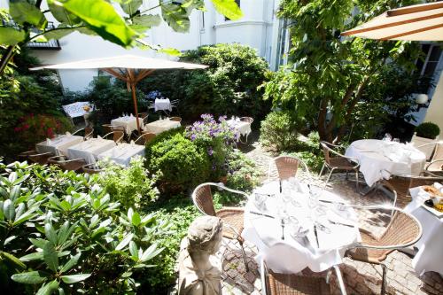 a garden area with tables, chairs, and plants at Aussen Alster Hotel in Hamburg