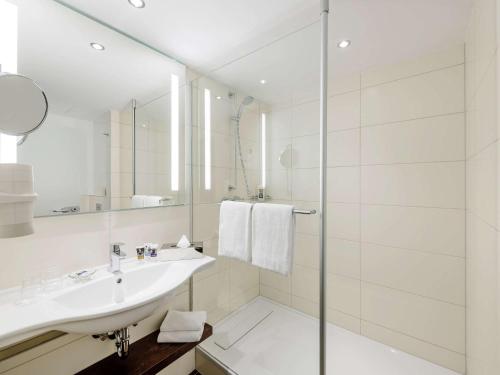 a bathroom with a sink, mirror and bath tub at Mercure Hotel Berlin City West in Berlin