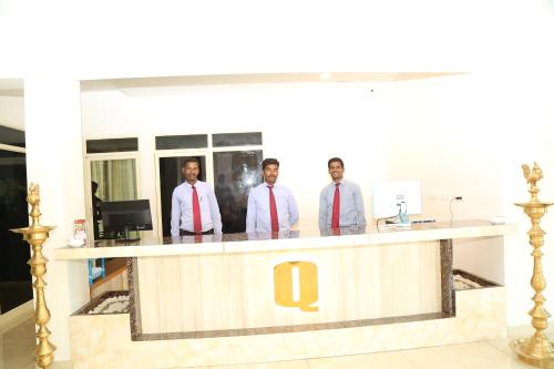 three men in ties standing at a reception counter at Hotel Queens Inn Velankanni in Velānganni