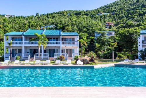 a house with a swimming pool in front of a mountain at Wyndham Tortola BVI Lambert Beach Resort in East End