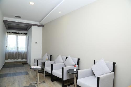 a waiting room with white chairs and a table at Hotel Queens Inn Velankanni in Velānganni