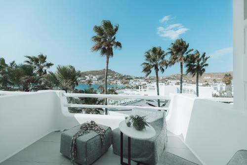 a balcony with palm trees and a table with luggage at Mykonos Blanc - Preferred Hotels & Resorts in Ornos
