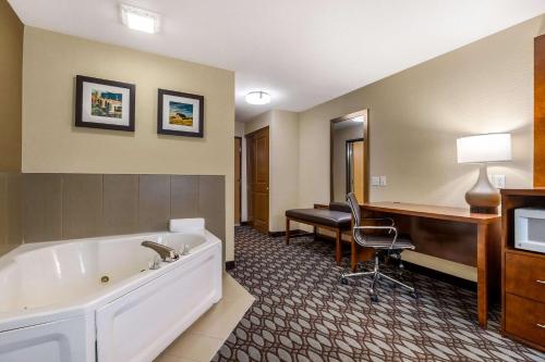 a hotel room with a tub and a desk and a computer at Comfort Inn in Story City