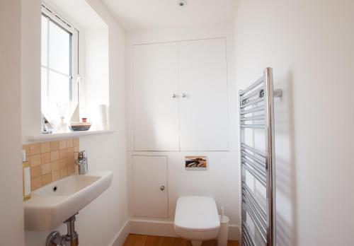 a white bathroom with a toilet and a sink at Whispers - 4 bedroom Luxury Family Holiday Home in Salcombe (Sleeps 8) in Salcombe