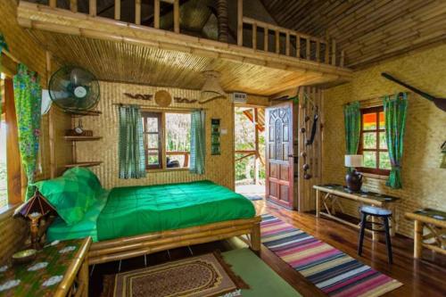 a bedroom with a green bed and a wooden ceiling at Treehouse Holidays-Lake View in Ko Yao Noi