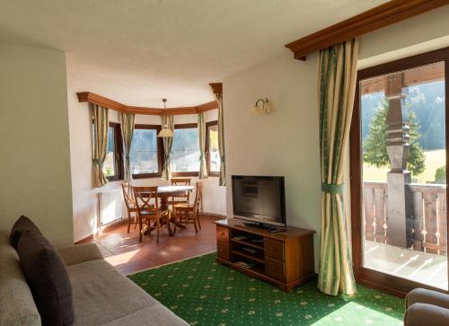 ein Wohnzimmer mit einem Sofa, einem TV und einem Tisch in der Unterkunft Ferienwohnungen Hirschen in Bichlbach