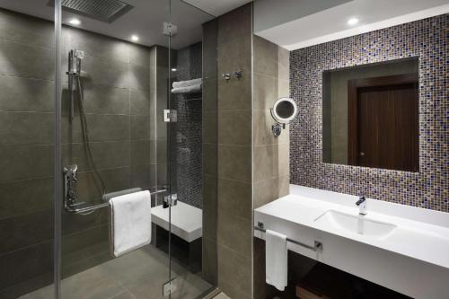 a bathroom with a sink and a shower with a mirror at Park Inn by Radisson Makkah Aziziyah in Makkah