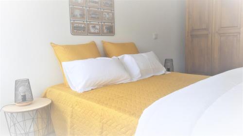 Cette chambre comprend un lit avec des draps jaunes et des oreillers blancs. dans l'établissement LOFT FORUM BRAGA 1, à Braga
