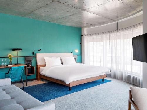 a bedroom with a white bed and a blue wall at Novotel Vladivostok in Vladivostok